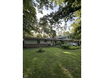 A charming home with a well-maintained lawn surrounded by mature trees at 9550 N Delaware St, Indianapolis, IN 46240