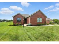 Beautiful red brick home with a well-manicured lawn and landscaping, under a blue sky with clouds at 1127 Kay Dr, Greenwood, IN 46142