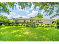 Charming one-story home with well-manicured lawn, colorful garden, and bright yellow exterior at 317 Stoner Dr, Anderson, IN 46013