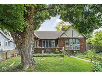 Charming brick home featuring a well-maintained front yard with mature trees and landscaping at 4901 N Kenwood Ave, Indianapolis, IN 46208