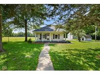 Charming home featuring a covered porch, beautiful landscaping, and mature trees on a well-maintained lawn at 6208 S 200 W, Trafalgar, IN 46181