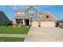 Inviting two-story home featuring brick accents, a well-manicured lawn, and a two-car garage at 6664 Kara Ln, Brownsburg, IN 46112