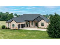 Attractive brick home with a three car garage, lush greenery, and a well-maintained lawn, exemplifying suburban charm at 7702 N County Road 300 W, Lizton, IN 46149