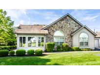 Charming single-story home featuring a stone accent wall, manicured lawn and verdant green bushes at 7919 Cool Hollow Pl, Indianapolis, IN 46237