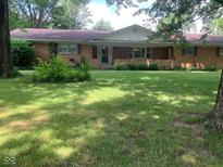 Ranch home featuring a brick facade, covered front porch, and a spacious, grassy front yard with mature trees at 106 N 300 W, Greenfield, IN 46140