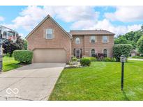 Charming brick home with a manicured lawn, mature trees, and a basketball hoop in the driveway at 11123 Garrick St, Fishers, IN 46038