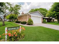 Charming brick home featuring an attached two-car garage and well-manicured lawn at 1540 Roanoke Dr, Zionsville, IN 46077