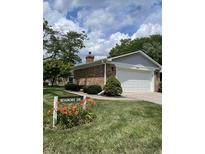 Charming home featuring a well-maintained lawn, flower beds, and a brick exterior with a two-car garage at 1540 Roanoke Dr, Zionsville, IN 46077