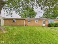 A brick home exterior is showcased with a green lawn and trees, offering a serene backyard view at 203 Plum E St, Frankton, IN 46044
