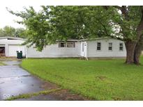 Exterior view of a home with white siding, surrounded by lush greenery and a mature tree at 220 S 2Nd St, Summitville, IN 46070