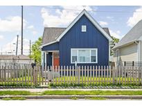 Charming blue home featuring a well-manicured lawn, a picket fence and a bright orange front door at 413 E Caven St, Indianapolis, IN 46225