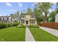 Charming yellow two-story home featuring a well-manicured lawn and inviting front porch at 5715 Oak Ave, Indianapolis, IN 46219