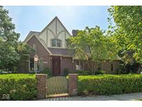 Charming brick home with Tudor-style accents and a well-manicured front yard and wooden gate at 6733 Jons, Zionsville, IN 46077