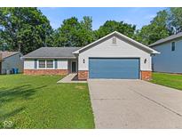 Charming single-story home featuring a blue garage door, siding, brick accents, and lush green lawn at 834 Delray Dr, Indianapolis, IN 46241
