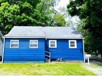 Charming blue home with a well-maintained lawn and mature trees surrounding the property at 94 N Routiers Ave, Indianapolis, IN 46219