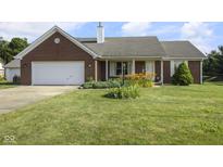 Charming red brick ranch home featuring an attached two-car garage and a well-manicured front yard at 1016 W Creek Ridge Dr, Fountaintown, IN 46130