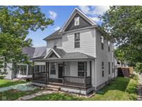 Charming two-story home featuring a covered front porch, classic white siding, and lush landscaping at 2001 S Jefferson St, Muncie, IN 47302