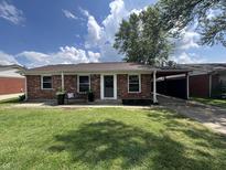 Charming brick home featuring a well-manicured lawn and cozy front porch seating area at 2845 12Th St, Columbus, IN 47201