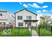 Charming two-story home with black fence, lush lawn, and bright, inviting curb appeal at 35 N Keystone Ave, Indianapolis, IN 46201