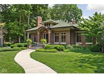 Charming brick home with a green tile roof, landscaped yard, and a winding walkway at 4455 Broadway St, Indianapolis, IN 46205