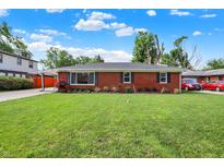 Charming brick home with a well-maintained lawn and mature trees on a sunny day at 5015 Nowland Ave, Indianapolis, IN 46201