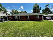 Charming one-story brick home featuring a well-manicured lawn and lush landscaping under a bright blue sky at 5015 Nowland Ave, Indianapolis, IN 46201