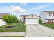 Charming two-story home with a well-manicured lawn, two-car garage and a lovely tree at 5305 Traditions Rd, Indianapolis, IN 46235