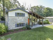 Two story home featuring a covered porch, stone accents, and lush landscaping at 6019 S Tacoma Ave, Indianapolis, IN 46227