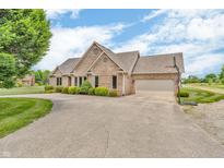 Lovely brick home featuring an attached two-car garage and well-maintained landscaping at 7304 E Stop 11 Rd, Indianapolis, IN 46259