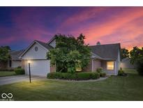 Charming home with a well-maintained lawn, mature tree, and a two-car garage under a colorful, vibrant sky at 8213 Thoroughbred Run, Indianapolis, IN 46256