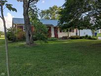 A single-story home with a well-manicured lawn and mature trees under a sunny sky at 8923 Maze Rd, Indianapolis, IN 46259