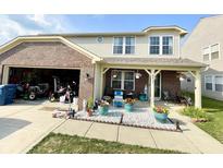 Two-story home featuring a covered front porch, brick accents, and an attached garage filled with recreation equipment at 9628 Gull Lake Dr, Indianapolis, IN 46239