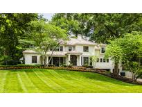 Elegant home with manicured lawn, lush landscaping, and a charming front entrance framed by mature trees at 110 Bow Ln, Indianapolis, IN 46220