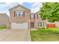 Charming two-story brick home with a well-maintained lawn, attached two car garage and inviting entryway at 1449 Danielle Dr, Indianapolis, IN 46231