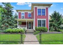Charming red two-story home with a landscaped front yard, black fence, and a welcoming front porch with flowers at 2263 Glebe St, Carmel, IN 46032