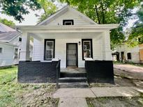 Charming white home featuring a covered front porch with painted brick and updated entry door at 405 N Bradley Ave, Indianapolis, IN 46201