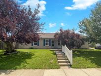 Charming single-story home with a well-maintained front lawn, white picket fence, and inviting entryway at 5210 Sandy Forge Dr, Indianapolis, IN 46221