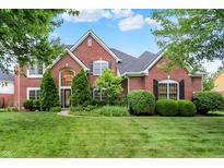 Stunning two-story brick home featuring a manicured lawn and mature trees at 5761 Coopers Hawk Dr, Carmel, IN 46033