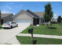 Charming one story home with white brick, manicured lawn, and an attached two car garage at 7232 Moultrie Dr, Indianapolis, IN 46217