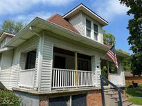 Charming two-story home with American flag, white siding, and covered front porch at 118 S Swain St, Ingalls, IN 46048