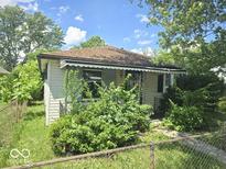 Modest single-story home with vintage architectural details surrounded by overgrown foliage at 1816 E Highland Ave, Muncie, IN 47303
