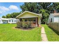Charming yellow bungalow featuring a covered front porch and lush green lawn at 3609 N Keystone Ave, Indianapolis, IN 46218