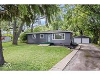 Charming single-story home featuring a well-manicured lawn and a detached two car garage at 5407 Adelaide St, Indianapolis, IN 46203