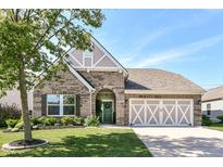 Charming brick home with a well-manicured lawn, arched entryway, and a two-car garage with white accents at 5765 White Pine Rd, Whitestown, IN 46075