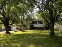 Traditional two-story home boasts a lush green lawn and mature trees that provide ample shade at 9138 E 18Th St, Indianapolis, IN 46229
