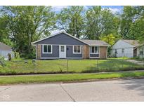 Charming single-story home featuring gray siding, brick accents, and a well-maintained front yard with mature trees at 9319 Rochelle Dr, Indianapolis, IN 46235