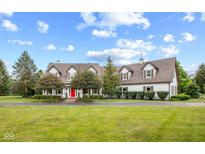 Sprawling two-story home featuring a red front door, mature trees, and a pristine lawn at 10594 Geist Rd, Fishers, IN 46037