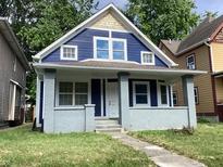 Charming blue two-story home with a brick-based porch and well-kept front lawn at 1125 N Rural St, Indianapolis, IN 46201