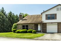 Charming brick townhouse featuring an attached garage, well-kept lawn, and mature trees at 2411 N Willow Way, Indianapolis, IN 46268