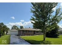 Charming one-story home with brick facade, green shutters, manicured lawn and detached garage at 7301 E Wiser Ave, Camby, IN 46113